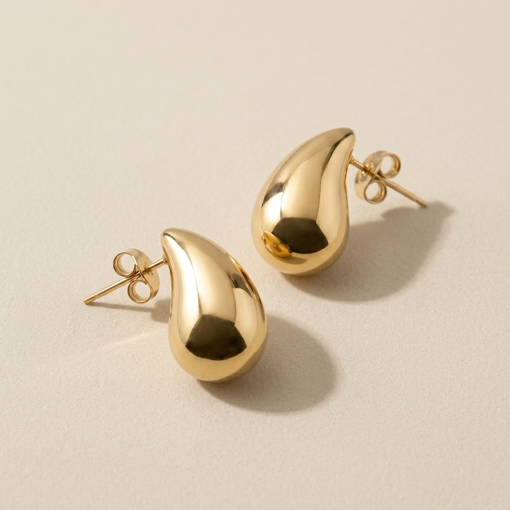 Pair of Morning Light Teardrop Earrings laid flat to show their rounded gold shape