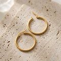 Pair of slim Meadow Hoop Earrings resting on pale travertine