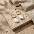 Rosebay Pearl Drop Earrings arranged on pale travertine with gold hoops and white pearls