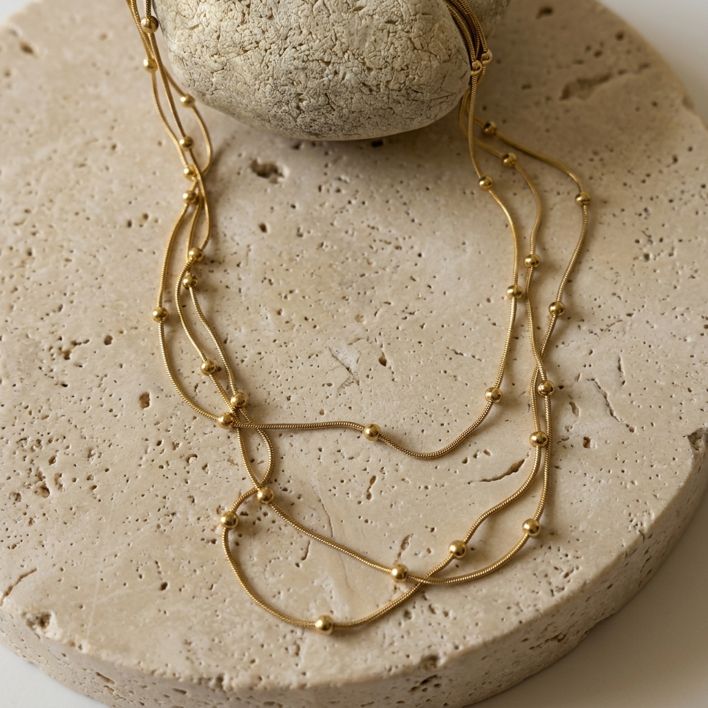 Close-up of the Celestial Layered Necklace arranged across pale travertine