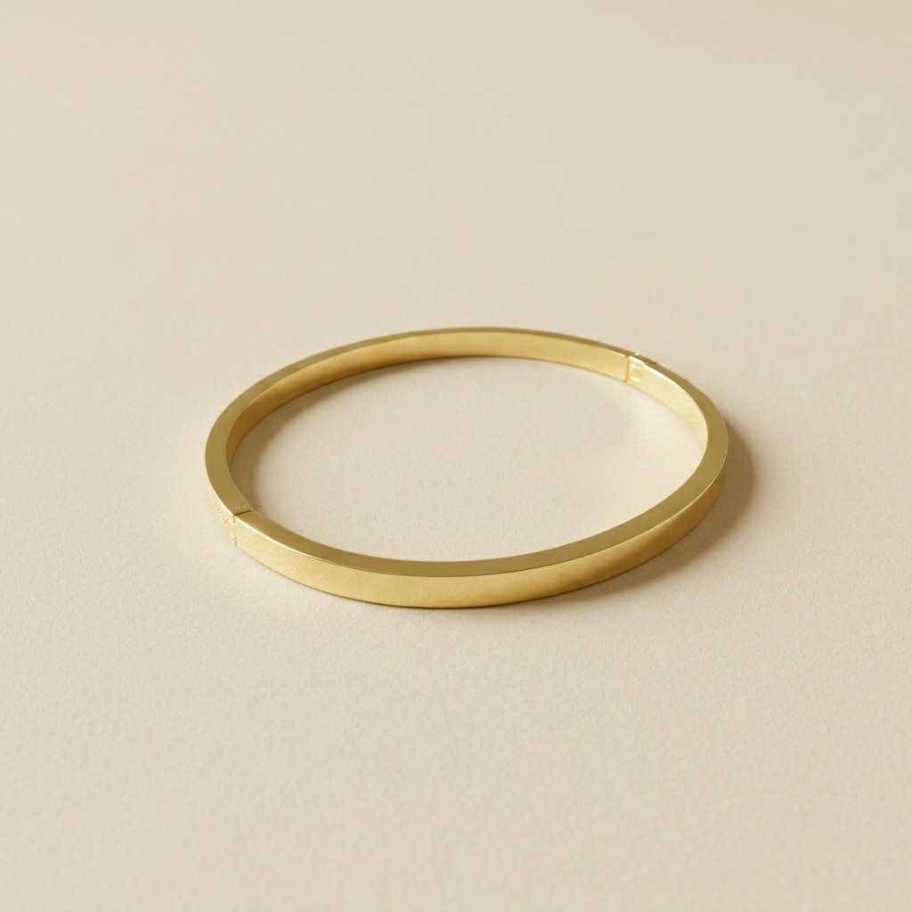 Meadow Hinged Bangle laid flat on a neutral background to show its slim oval shape