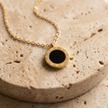 Cove Reversible Pendant Necklace showing the black glass side on pale travertine