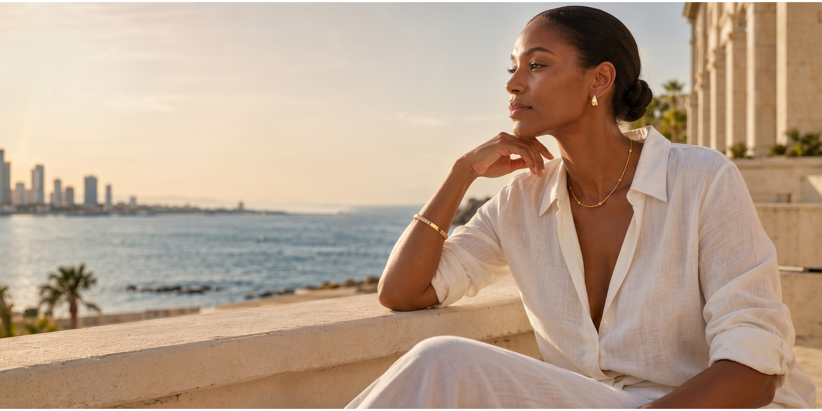 Woman by the sea wearing the Celestial Bead Necklace and gold teardrop earrings