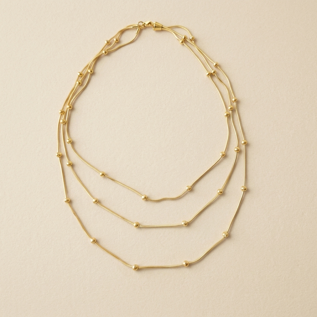 Celestial Layered Necklace laid flat to show its three fine chains and gold bead details